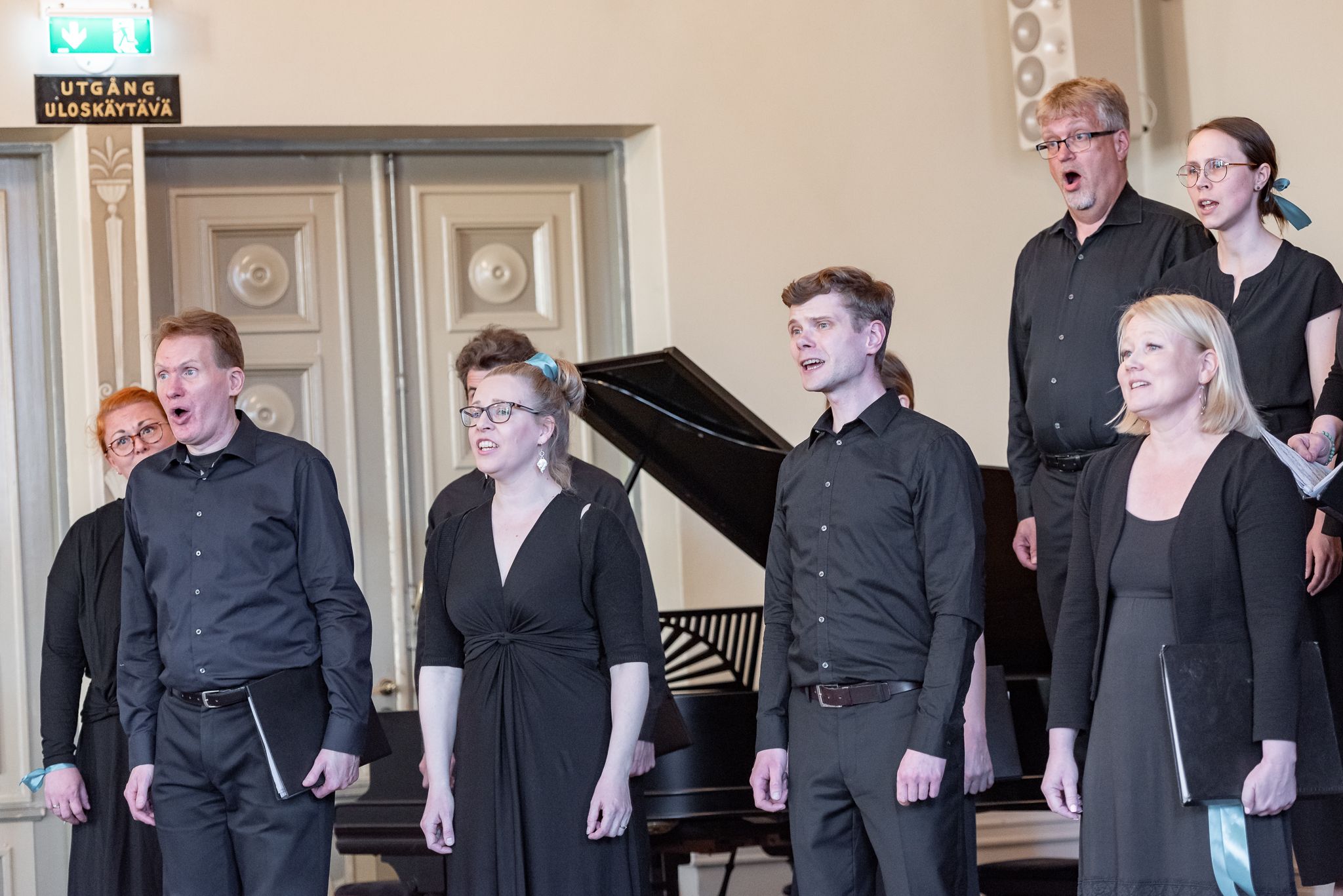 Mustiin pukeutuneet kuorolaiset laulamassa salissa