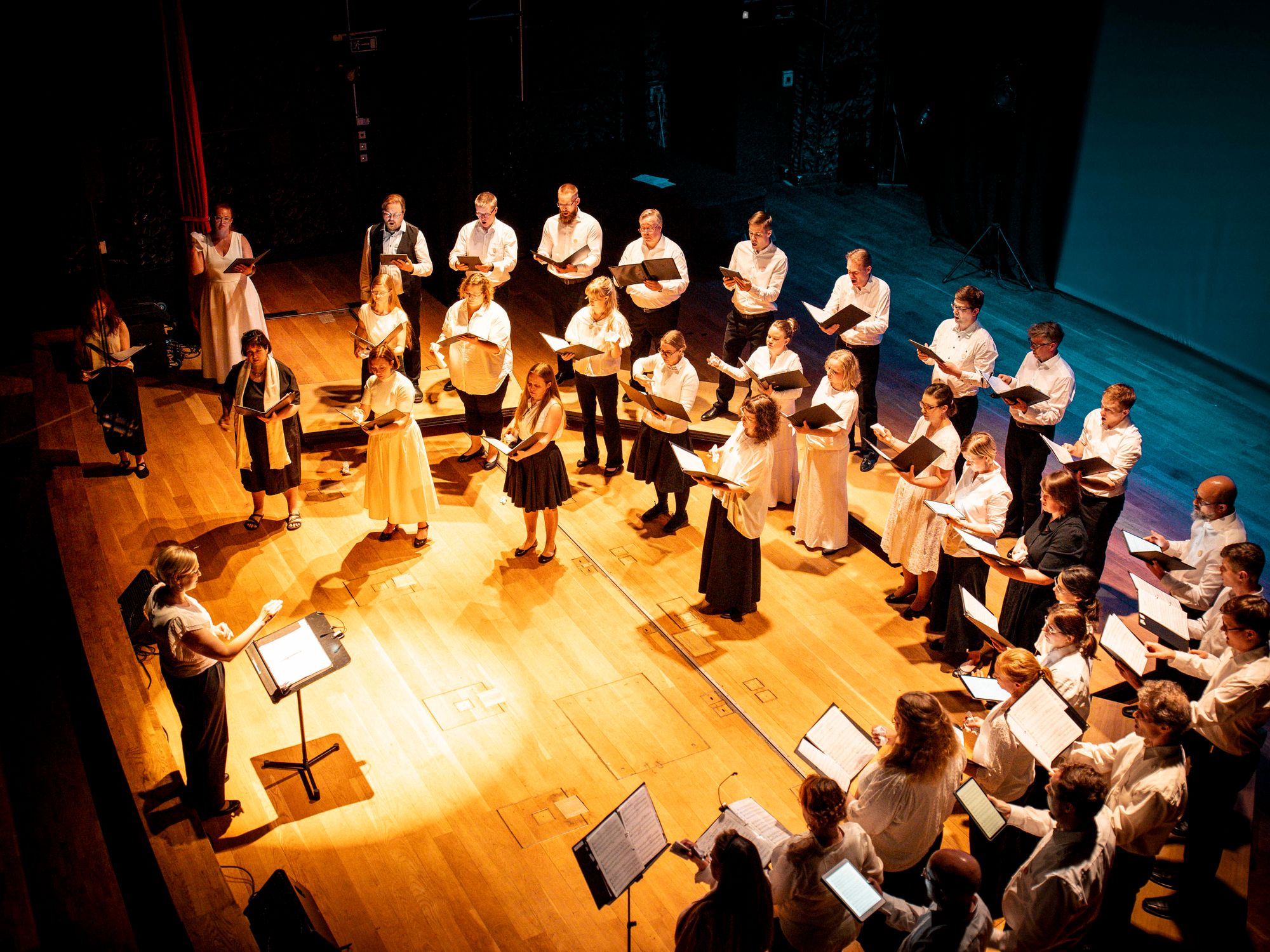 Kuoro esiintyy puolikaaressa kuoronjohtajan johdolla © Tuomas Tenkanen