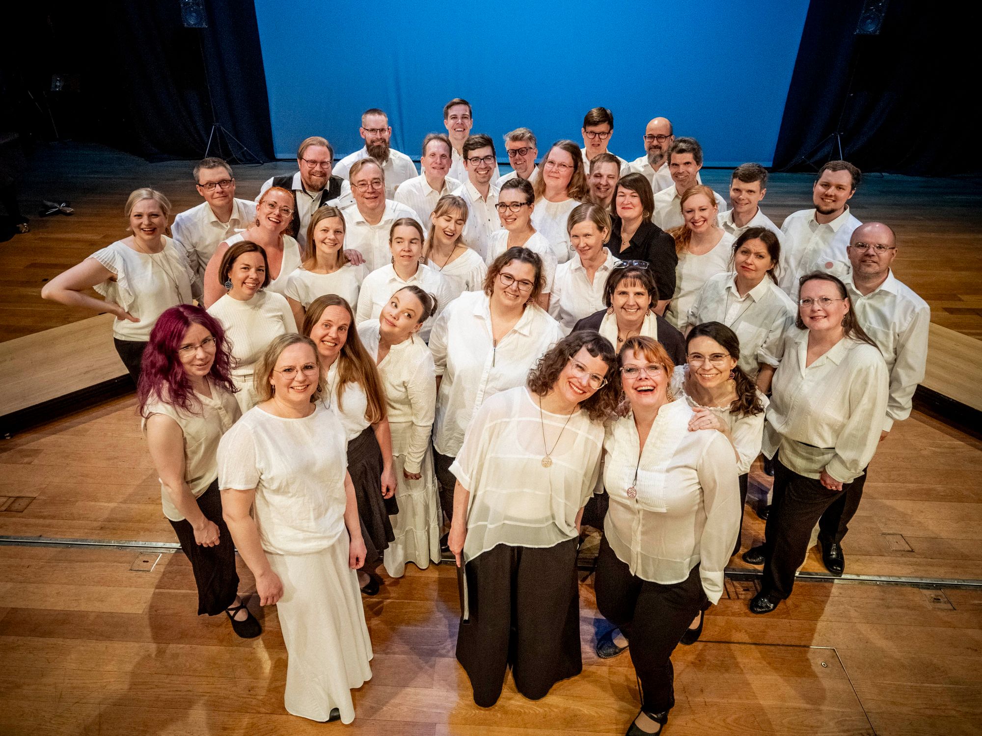 Kuorolaiset poseeraavat ryhmäkuvassa konserttilavalla © Tuomas Tenkanen